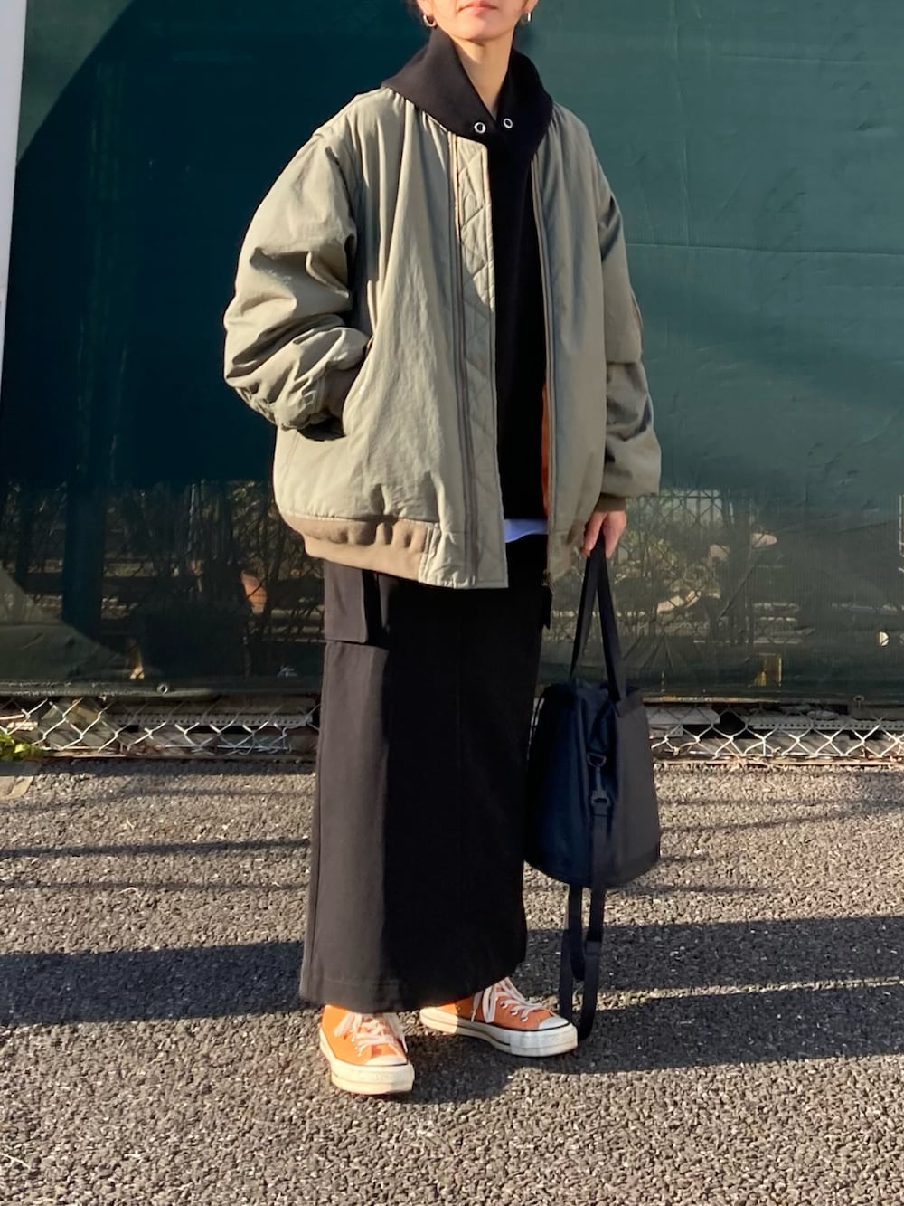 ブラック系のスカート、グリーン系のMA-1、ブラック系のパーカーを着用したレディースの春コーディネートの2枚目の写真