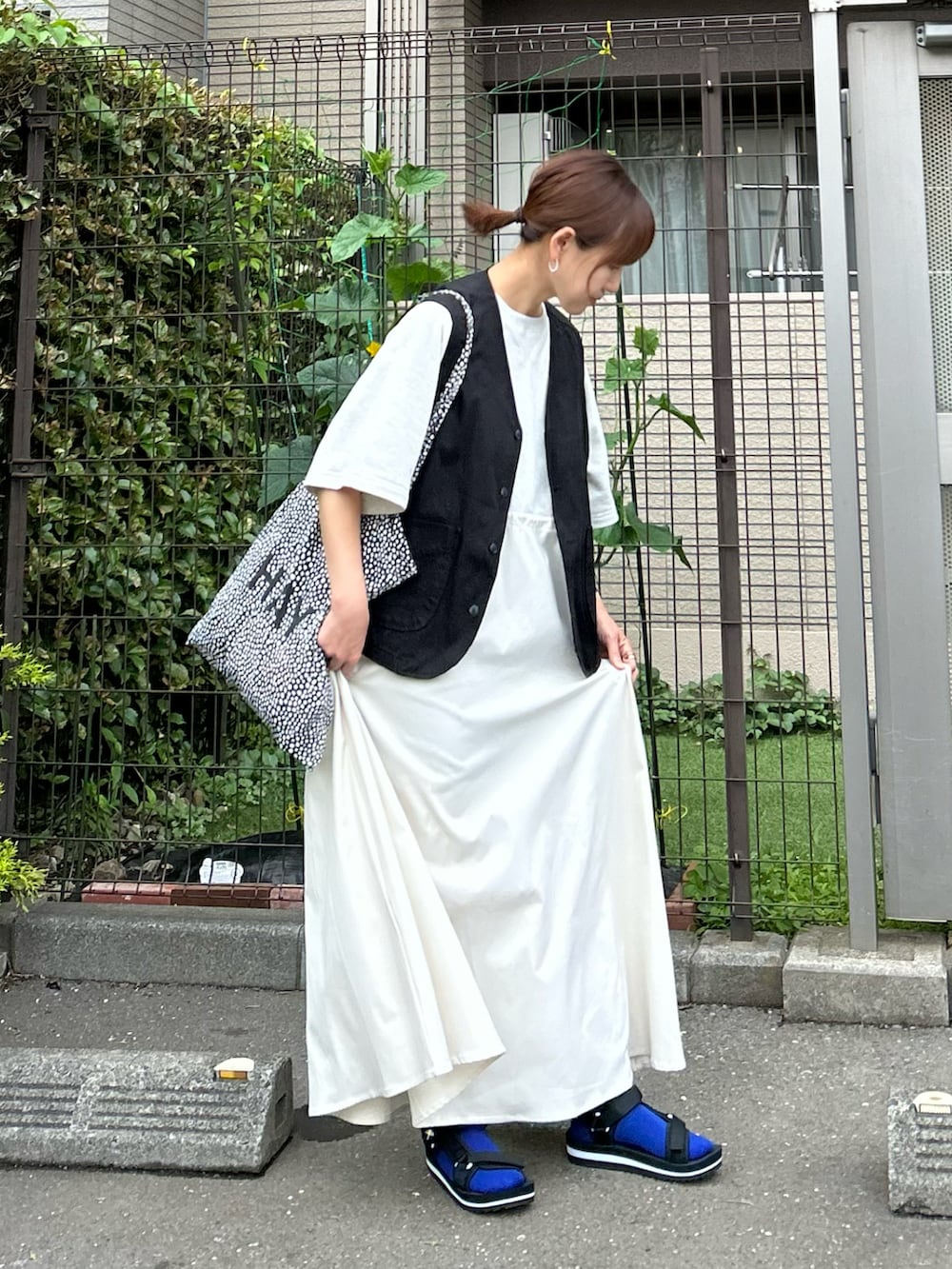 ベージュ系のワンピース、ブラック系のベスト、ブラック系のサンダルを着用したレディースの夏コーディネートの4枚目の写真