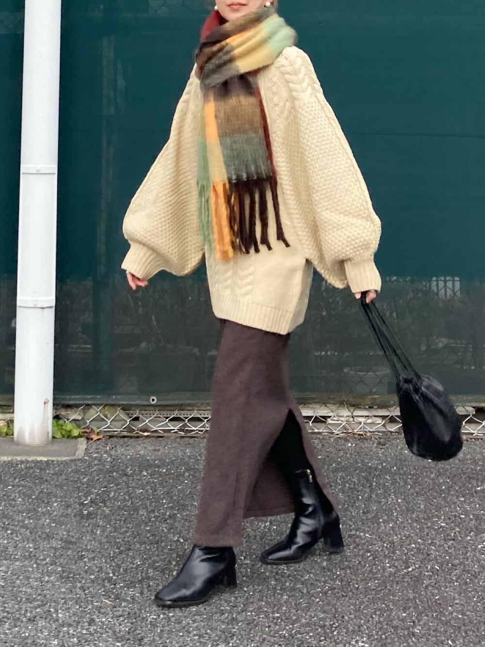 ホワイト系のニット/セーター、ブラウン系のスカート、ブラック系のハンドバッグを着用したレディースの冬コーディネートの3枚目の写真