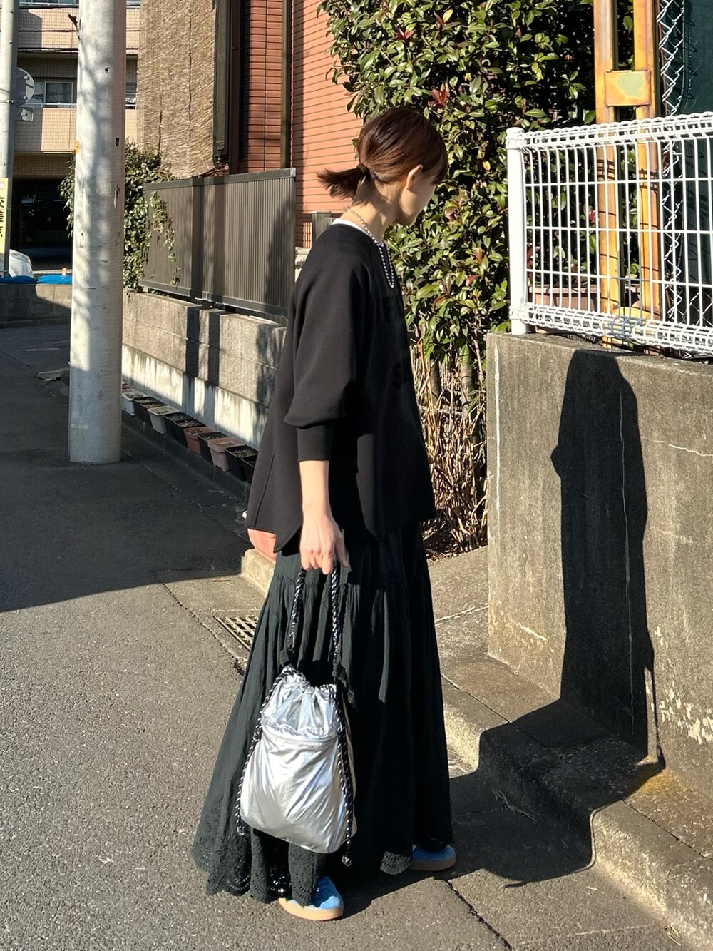 ブラック系のTシャツ/カットソー、ブラック系のスカート、シルバー系のショルダーバッグを着用したレディースの冬コーディネートの4枚目の写真
