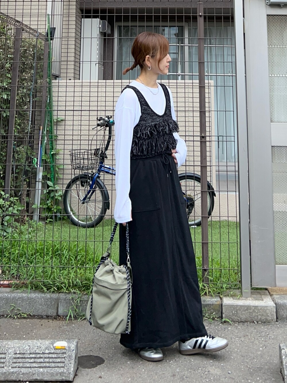 ブラック系のベスト、ホワイト系のTシャツ/カットソー、ブラック系のスカートを着用したレディースの秋コーディネートの2枚目の写真