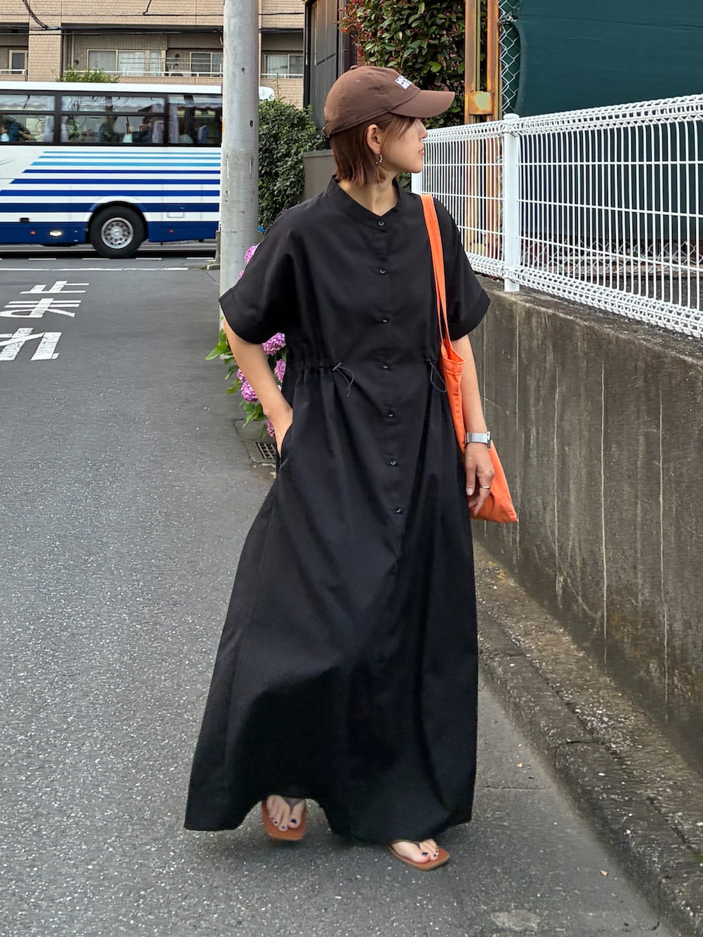 ブラック系のシャツワンピース、オレンジ系のトートバッグを着用したレディースの夏コーディネートの3枚目の写真