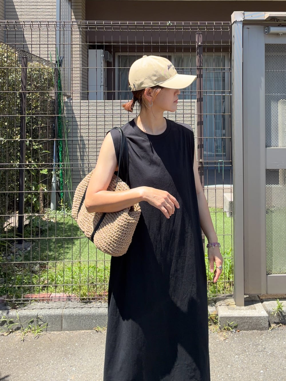 ブラック系のワンピース、イエロー系のトートバッグ、ベージュ系のキャップを着用したレディースの夏コーディネートの5枚目の写真
