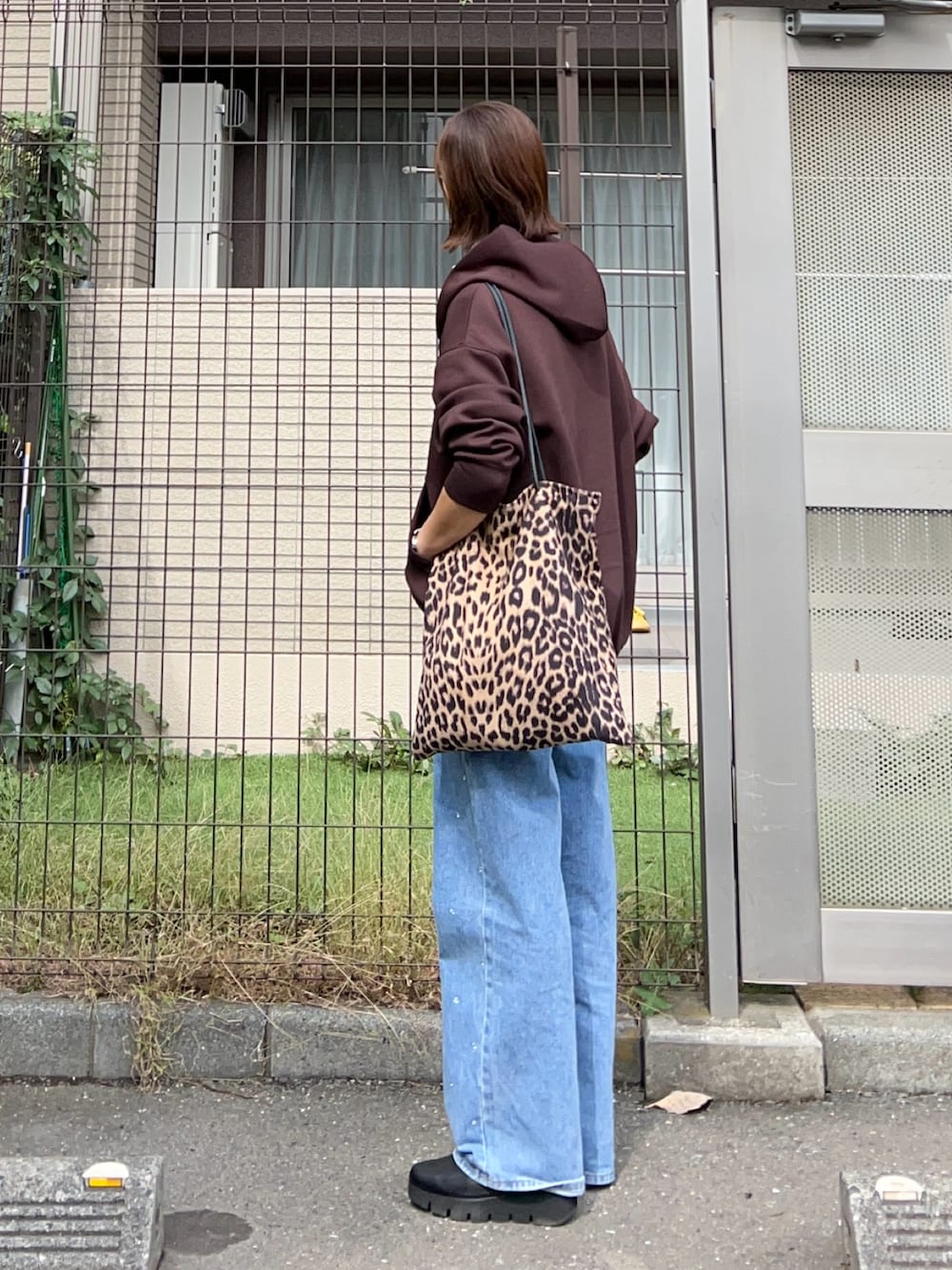 ブラウン系のパーカー、ブルー系のデニムパンツ、ブラウン系のトートバッグを着用したレディースの秋コーディネートの3枚目の写真
