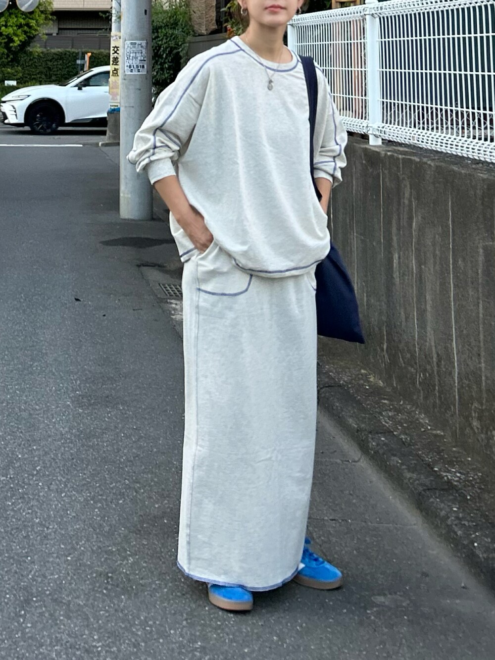 ベージュ系のTシャツ/カットソー、ベージュ系のスカート、ブルー系のトートバッグを着用したレディースの秋コーディネートの2枚目の写真