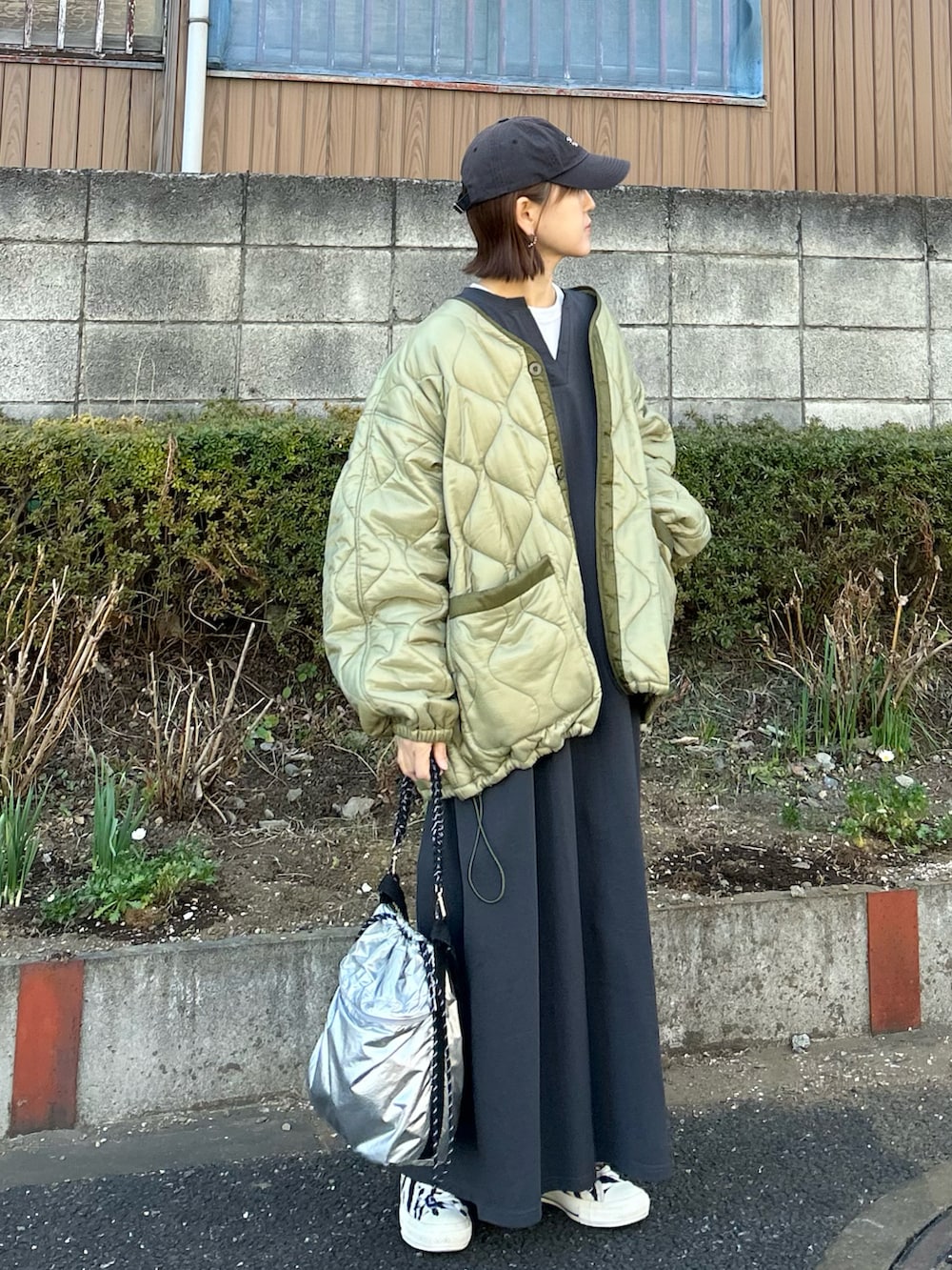 グリーン系のブルゾン、シルバー系のトートバッグ、グレー系のワンピースを着用したレディースの冬コーディネートの3枚目の写真