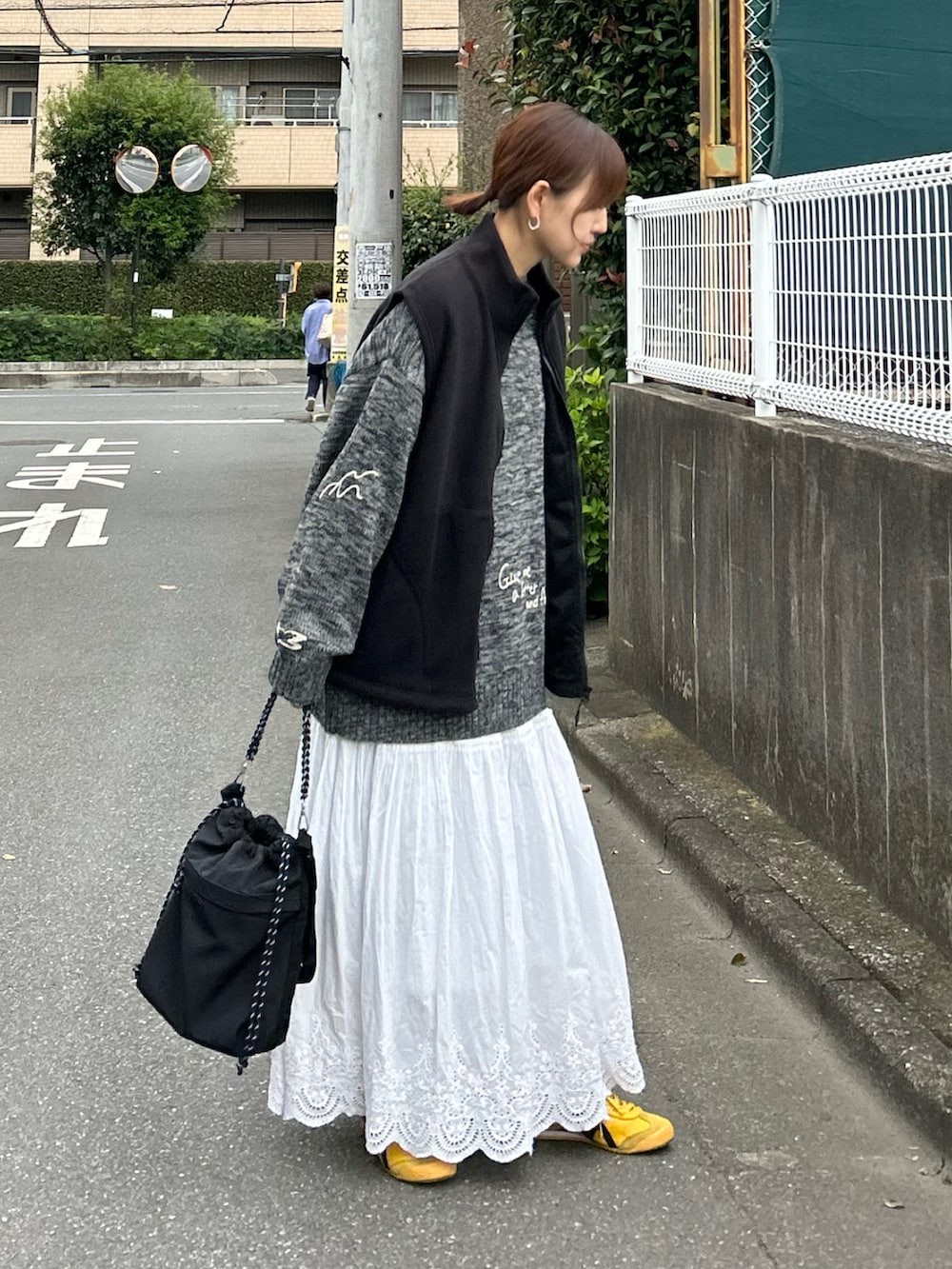 ブラック系のベスト、グレー系のニット/セーター、ブラック系のトートバッグを着用したレディースの秋コーディネートの2枚目の写真