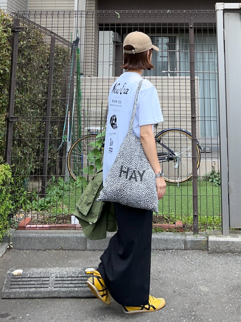 ホワイト系のTシャツ/カットソー、ブラック系のスカート、イエロー系のスニーカーを着用したレディースの夏コーディネートの2枚目の写真