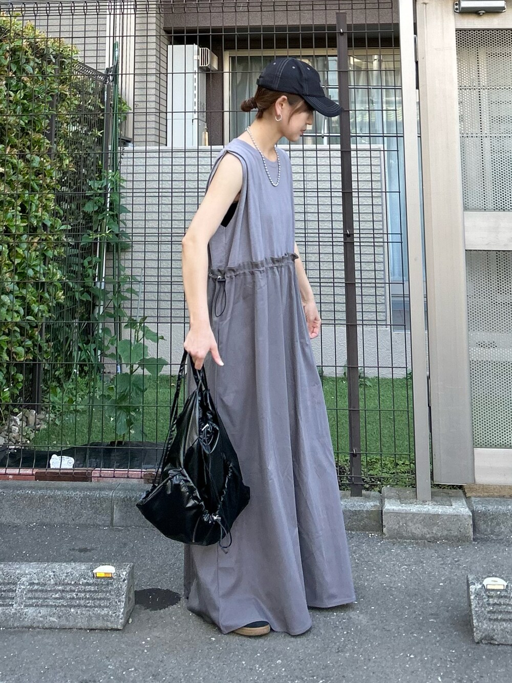 グレー系のワンピース、ブラック系のバックパック/リュック、ブラック系のキャップを着用したレディースの夏コーディネートの4枚目の写真