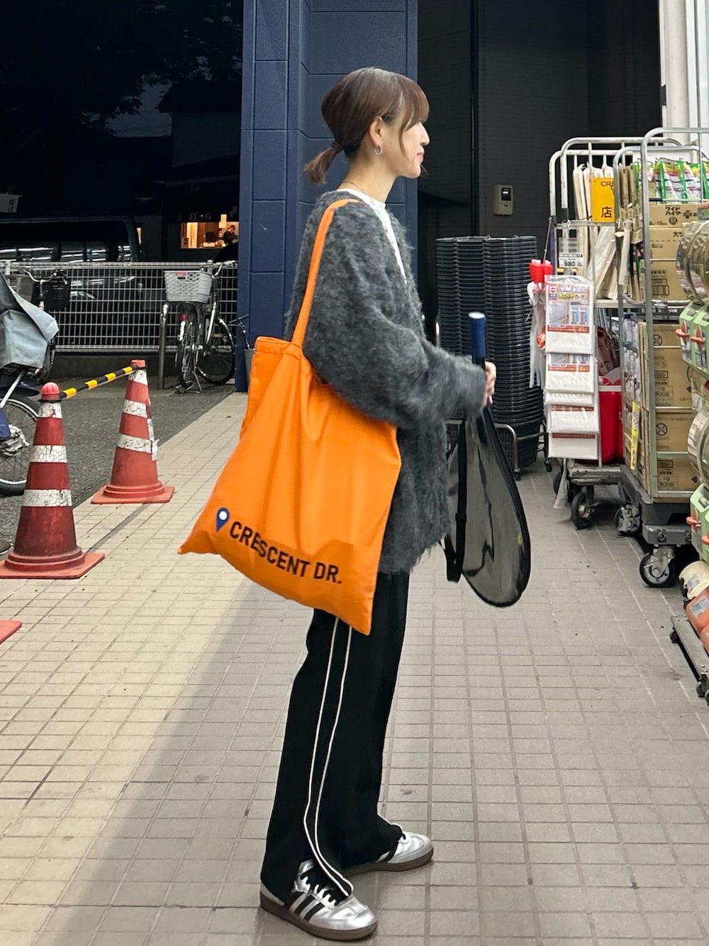 ブラック系のスウェットパンツ、オレンジ系のトートバッグ、グレー系のカーディガン/ボレロを着用したレディースの秋コーディネートの3枚目の写真