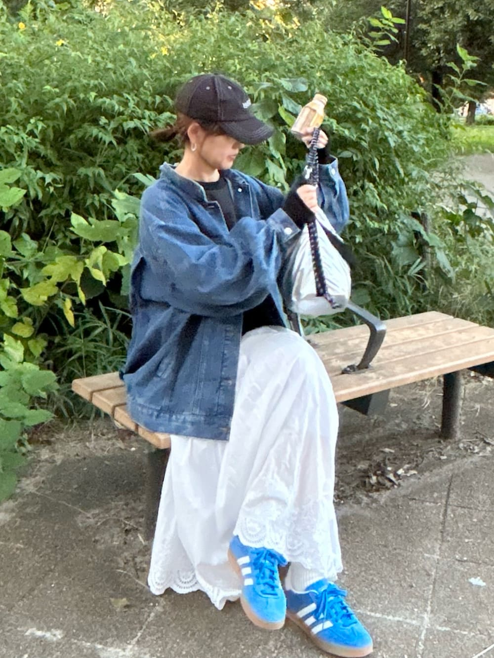 ホワイト系のスカート、ブルー系のデニムジャケット、ブラック系のスウェットを着用したレディースの秋コーディネートの3枚目の写真