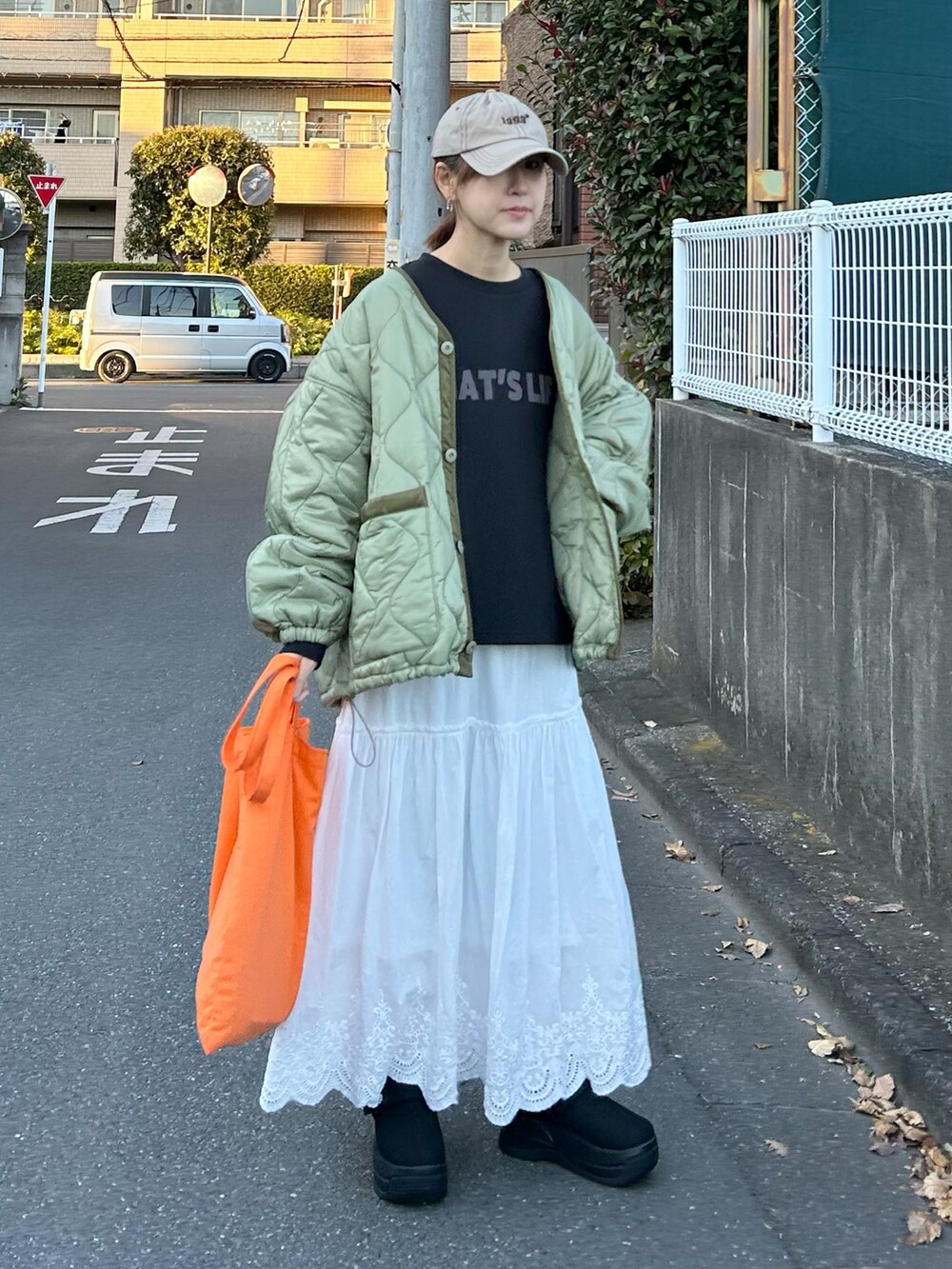ブラック系のTシャツ/カットソー、グリーン系のノーカラージャケット、ホワイト系のスカートを着用したレディースの冬コーディネートの3枚目の写真