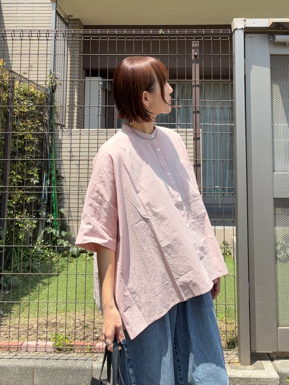 ピンク系のシャツ/ブラウス、ブルー系のデニムパンツ、ブラック系のショルダーバッグを着用したレディースの春コーディネートの5枚目の写真