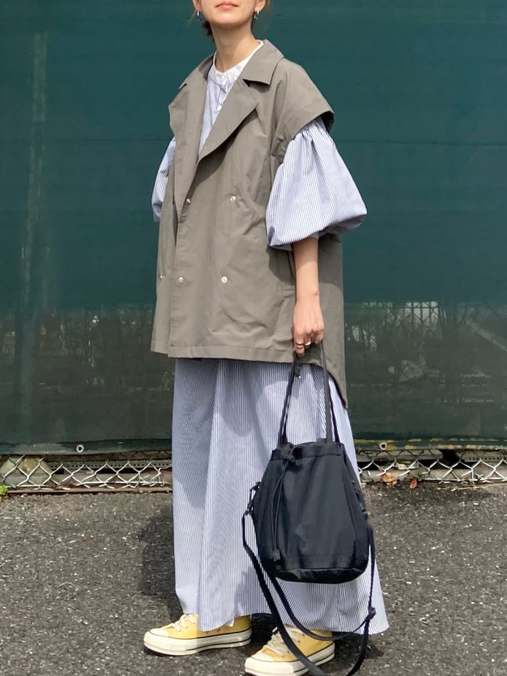 グレー系のミリタリージャケット、ブラック系のワンピース、ブラック系のバッグを着用したレディースの春コーディネートの3枚目の写真