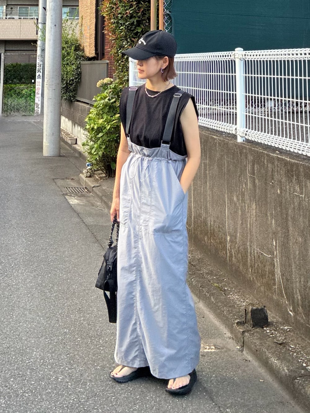 グレー系のジャンパースカート、ブラック系のサンダル、ブラック系のTシャツ/カットソーを着用したレディースの秋コーディネートの5枚目の写真