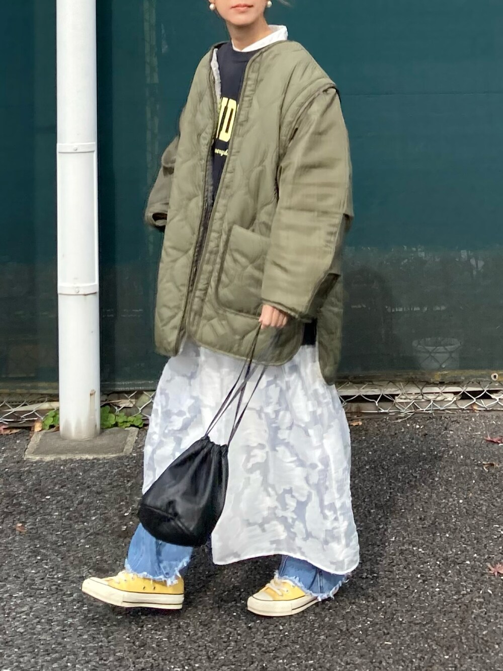 グリーン系のブルゾン、ブラック系のスウェット、ホワイト系のワンピースを着用したレディースの冬コーディネートの3枚目の写真