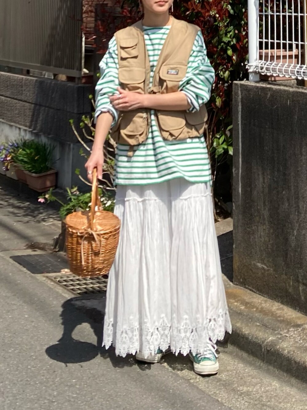 グリーン系のTシャツ/カットソー、ベージュ系のベスト、ホワイト系のスカートを着用したレディースの春コーディネートの3枚目の写真