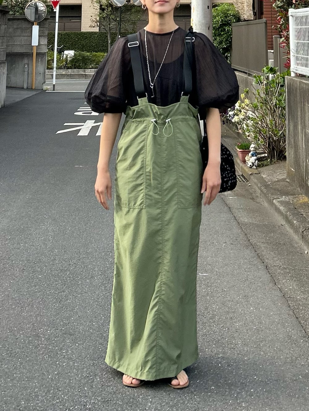 グリーン系のジャンパースカート、ブラック系のシャツ/ブラウス、ブラック系のショルダーバッグを着用したレディースの春コーディネートの2枚目の写真