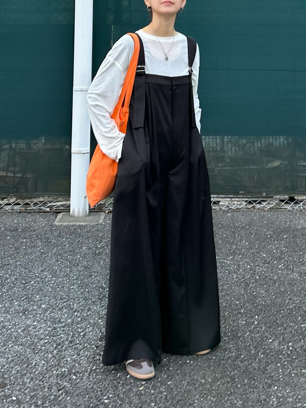 ブラック系のサロペット/オーバーオール、ホワイト系のTシャツ/カットソー、オレンジ系のトートバッグを着用したレディースの春コーディネートの2枚目の写真