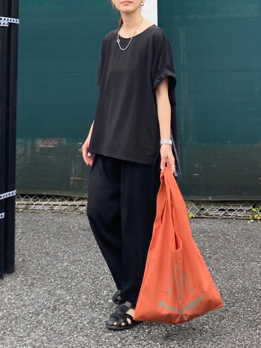 ブラック系のTシャツ/カットソー、ブラック系のその他パンツ、オレンジ系のトートバッグを着用したレディースの夏コーディネートの3枚目の写真