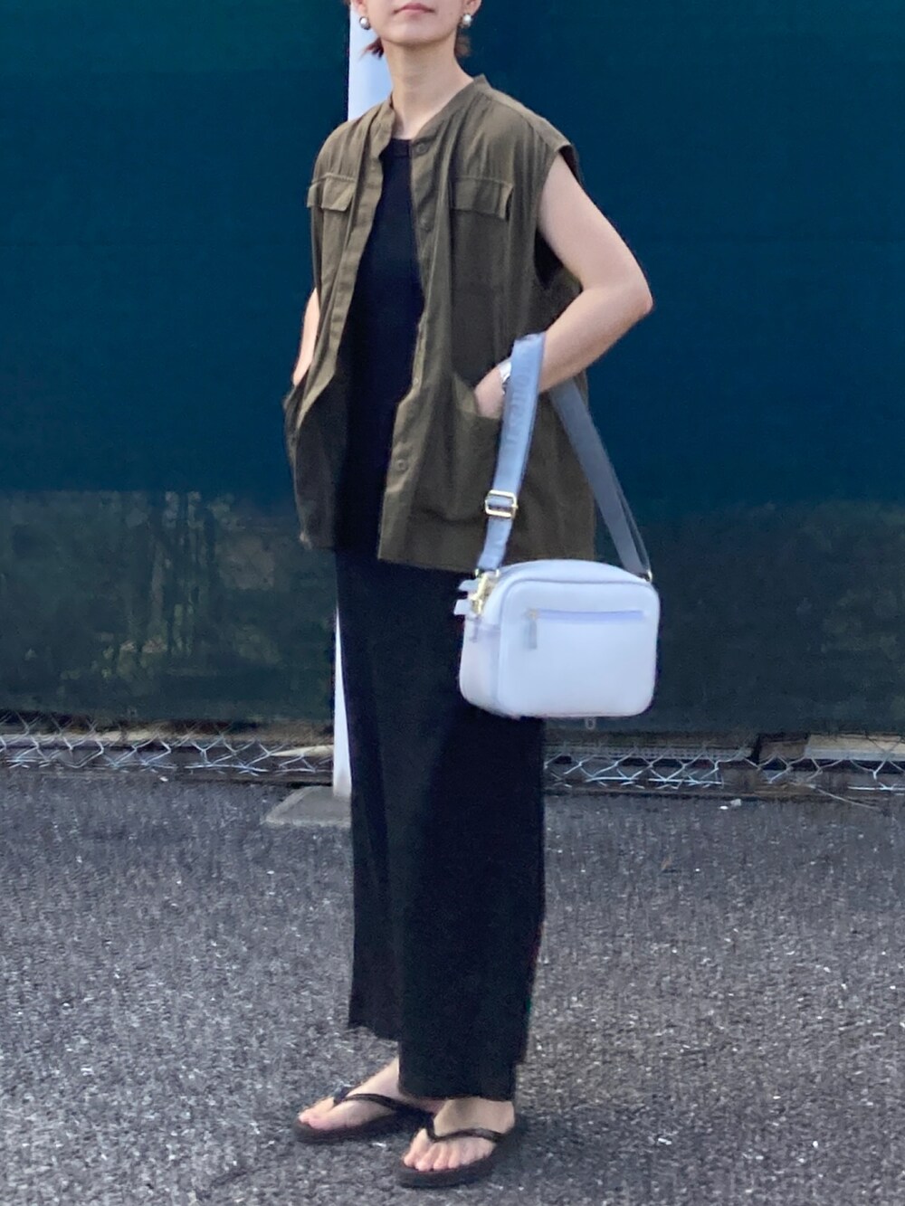 グリーン系のベスト、ブラック系のワンピース、ホワイト系のショルダーバッグを着用したレディースの夏コーディネートの3枚目の写真