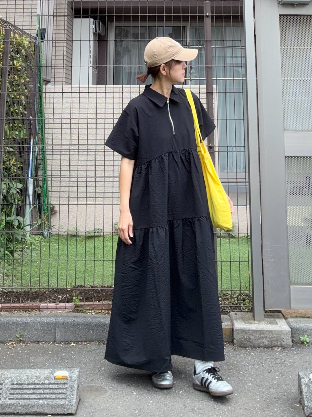 ブラック系のワンピース、イエロー系のトートバッグ、ベージュ系のキャップを着用したレディースの春コーディネートの4枚目の写真