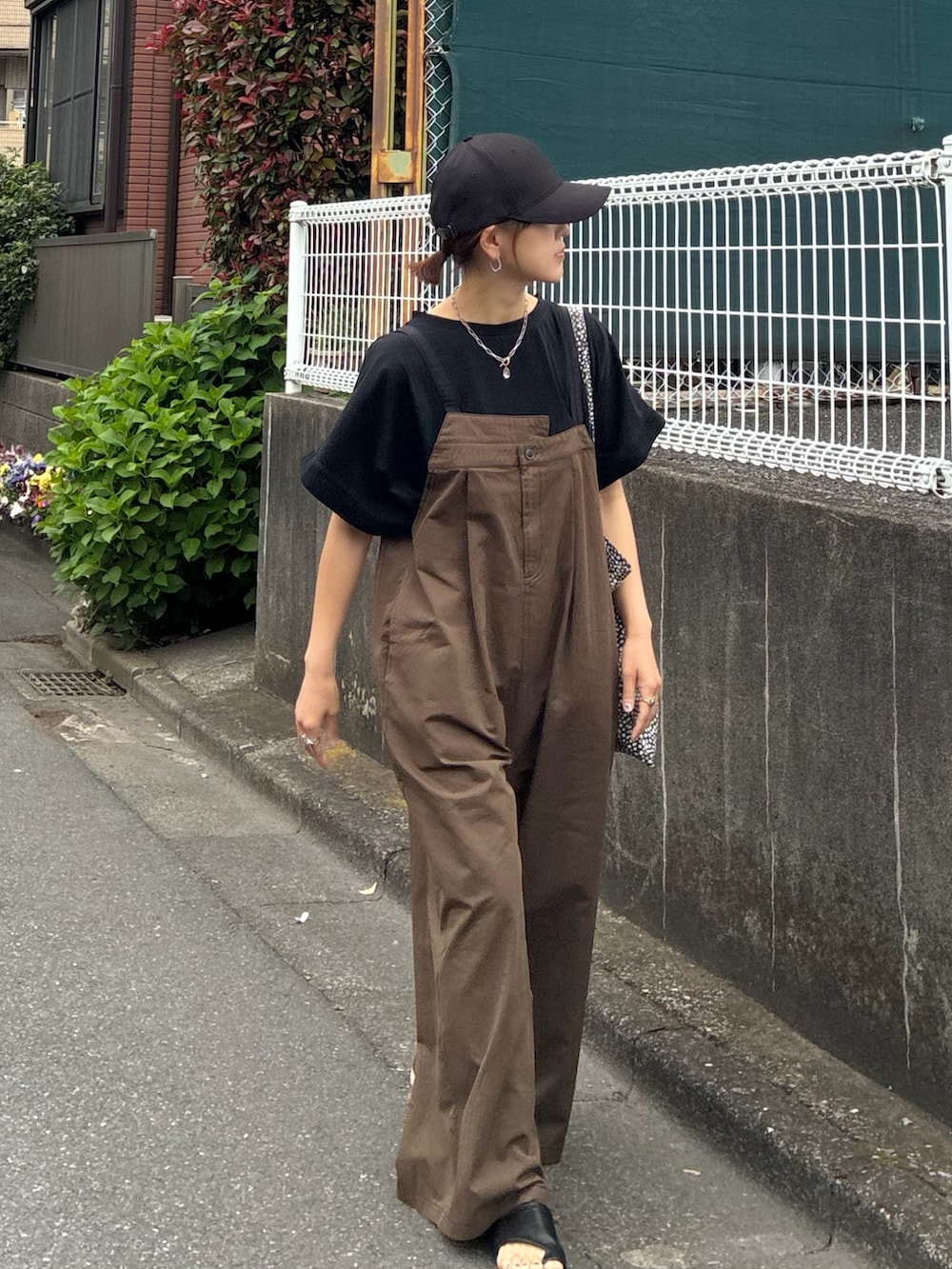 ブラック系のTシャツ/カットソー、ブラウン系のサロペット/オーバーオール、ブラック系のキャップを着用したレディースの春コーディネートの4枚目の写真