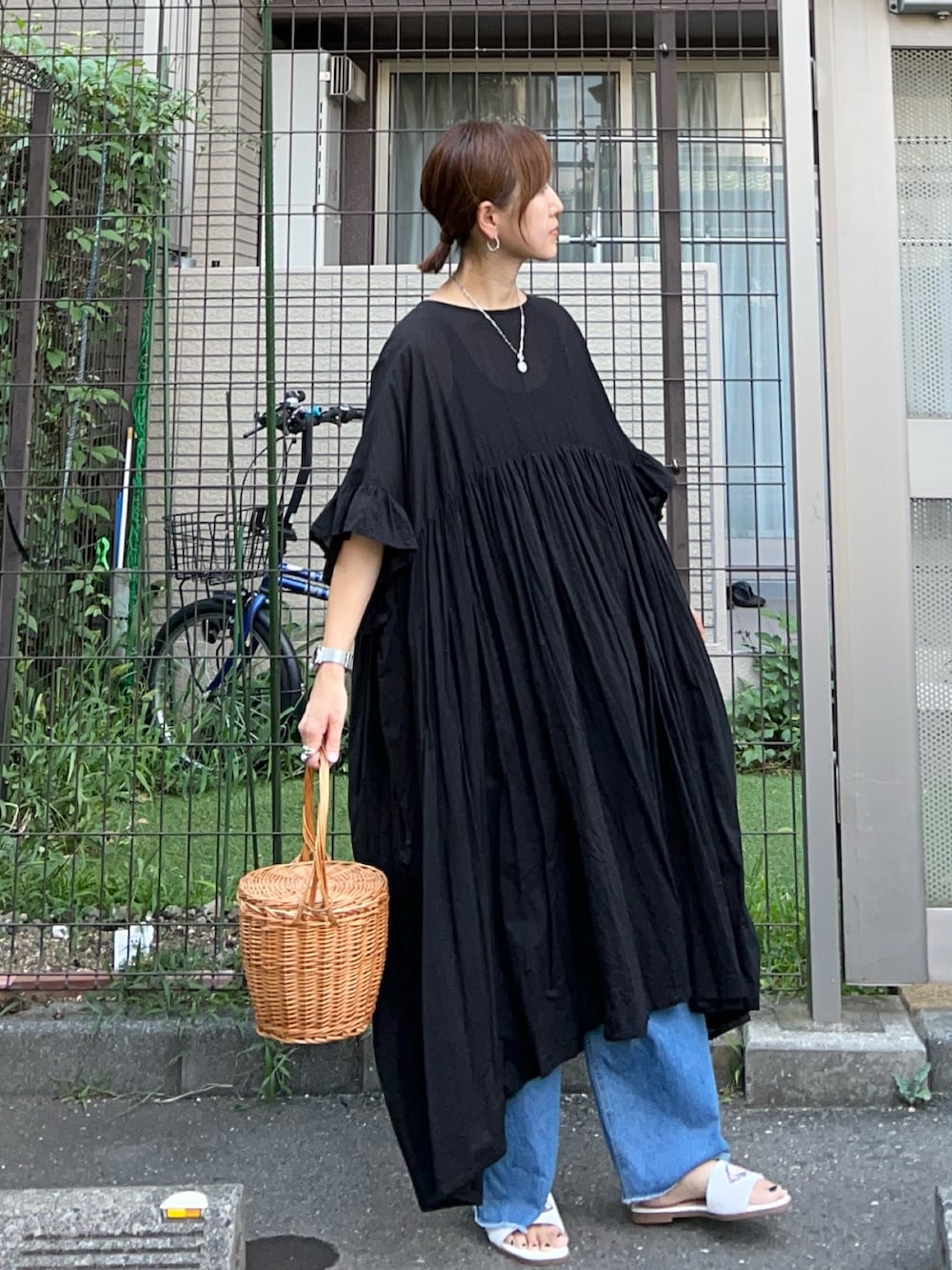 ブラック系のワンピース、ブルー系のデニムパンツ、ホワイト系のサンダルを着用したレディースの夏コーディネートの2枚目の写真