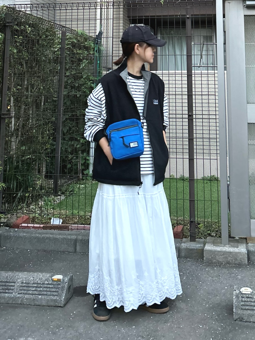 ブラック系のベスト、ブルー系のショルダーバッグ、ブラック系のTシャツ/カットソーを着用したレディースの秋コーディネートの4枚目の写真