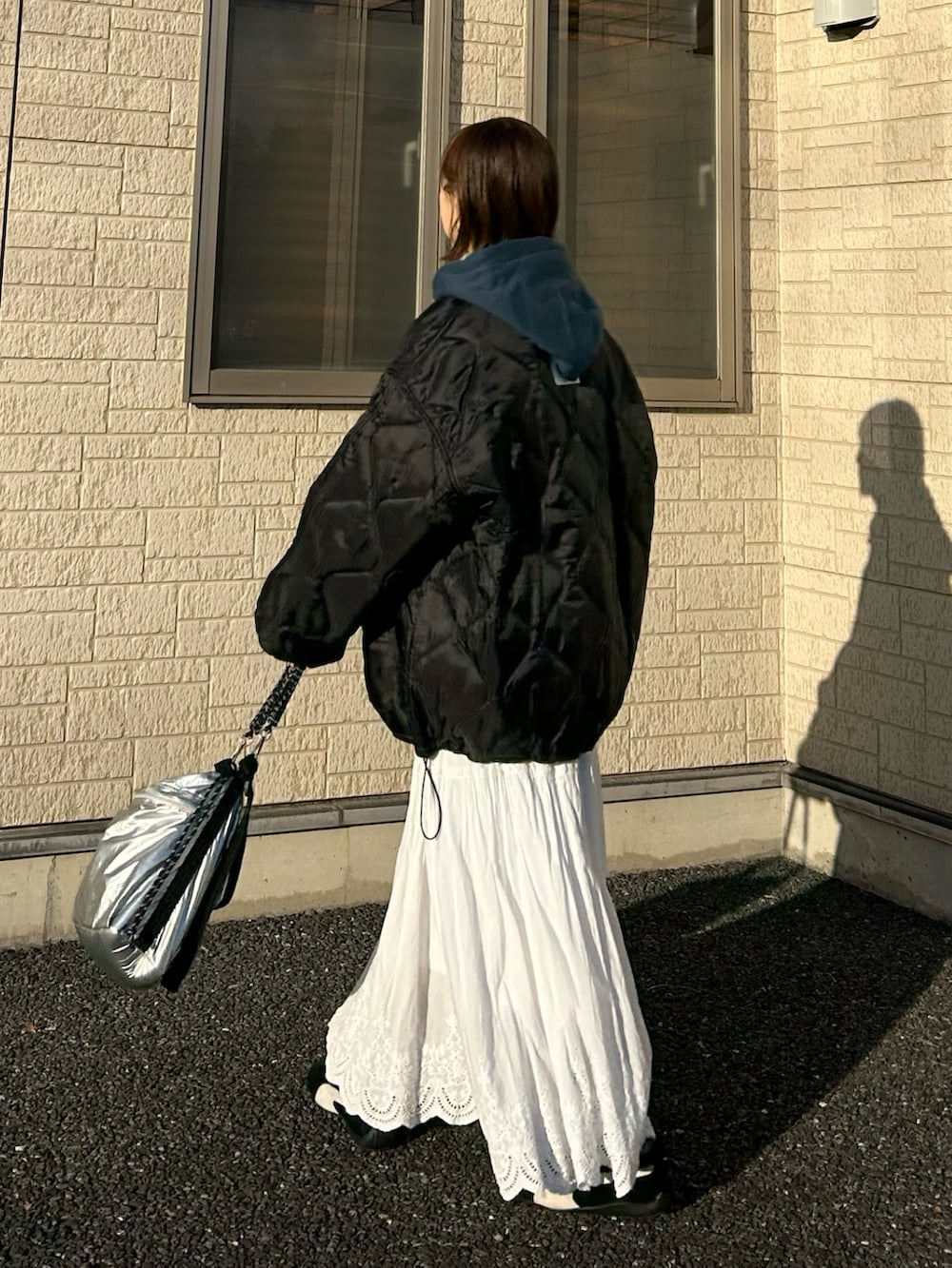 ブラック系のブルゾン、ブルー系のパーカー、シルバー系のトートバッグを着用したレディースの冬コーディネートの4枚目の写真