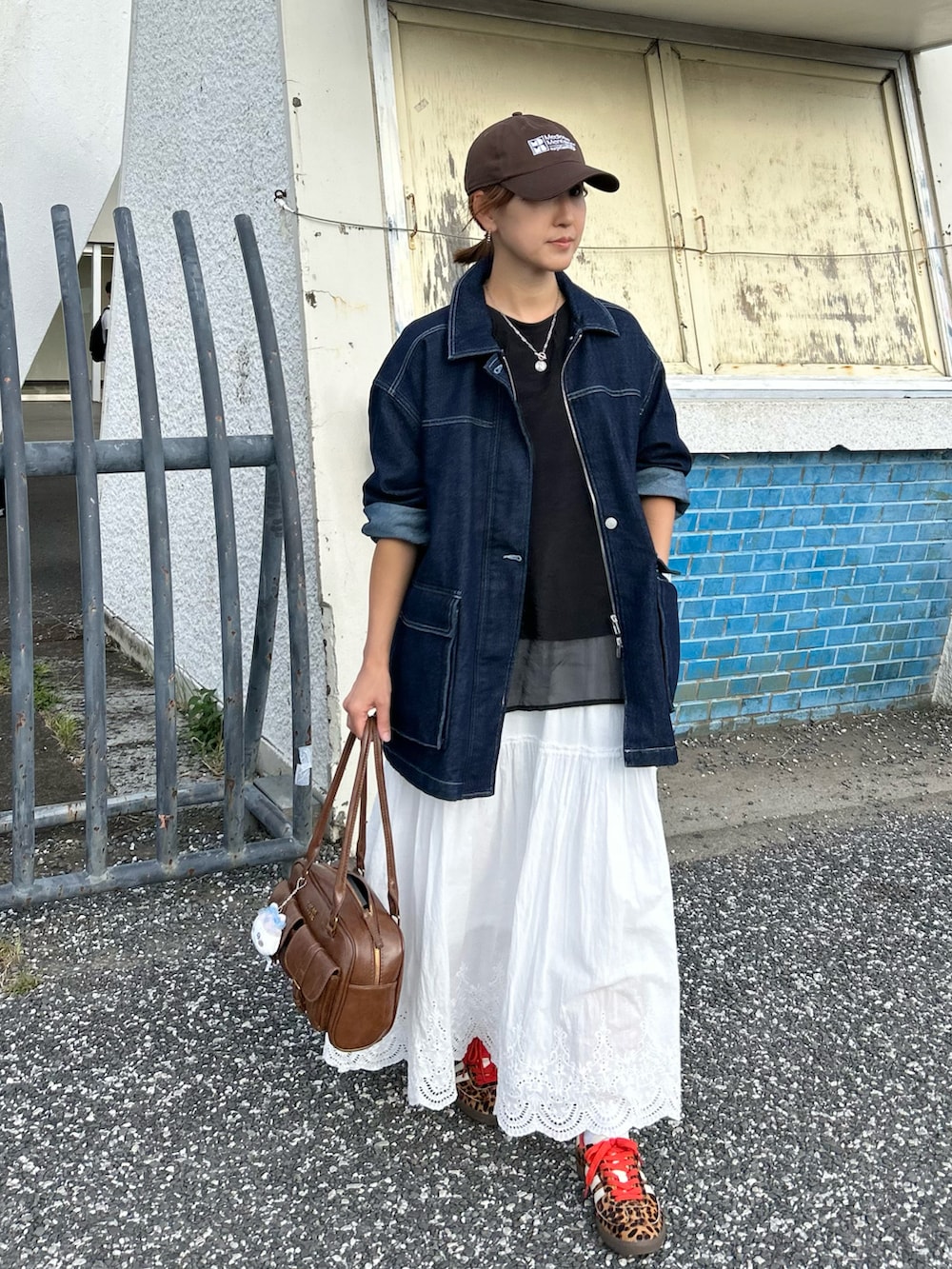 ホワイト系のスカート、ブラウン系のハンドバッグ、ブルー系のデニムジャケットを着用したレディースの秋コーディネートの3枚目の写真