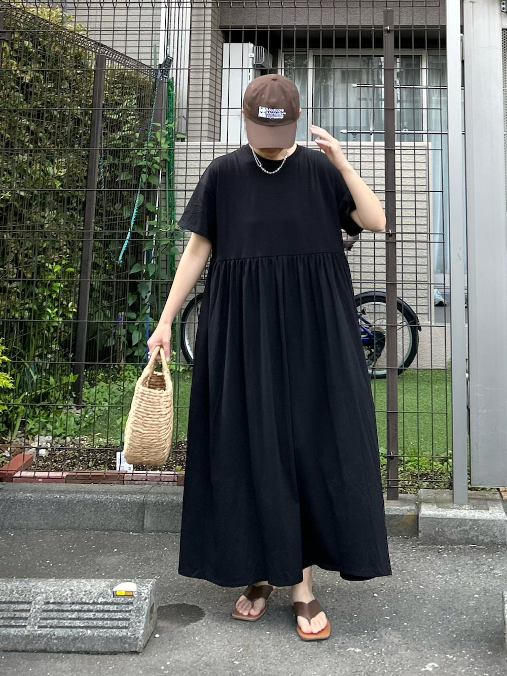 ブラック系のワンピース、ベージュ系のかごバッグ、シルバー系のリングを着用したレディースの夏コーディネートの3枚目の写真