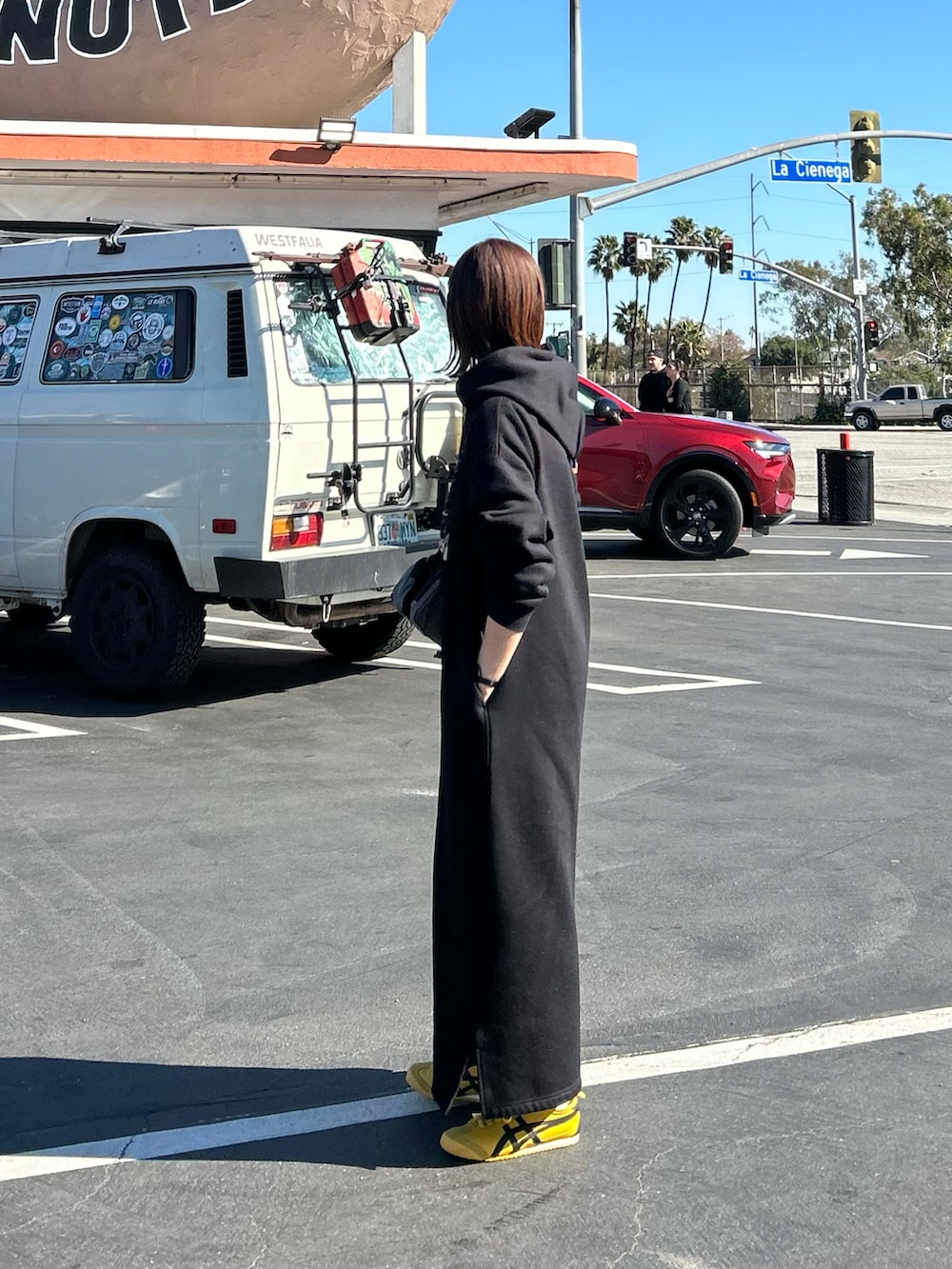 ブラック系のワンピース、グレー系のショルダーバッグ、イエロー系のスニーカーを着用したレディースの冬コーディネートの2枚目の写真