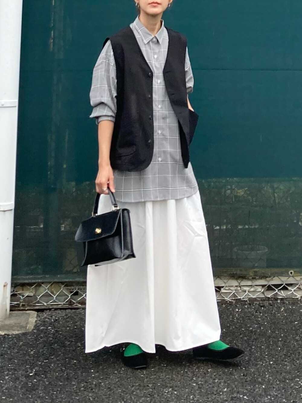 ブラック系のベスト、ホワイト系のスカート、ブラウン系のシャツ/ブラウスを着用したレディースの夏コーディネートの3枚目の写真