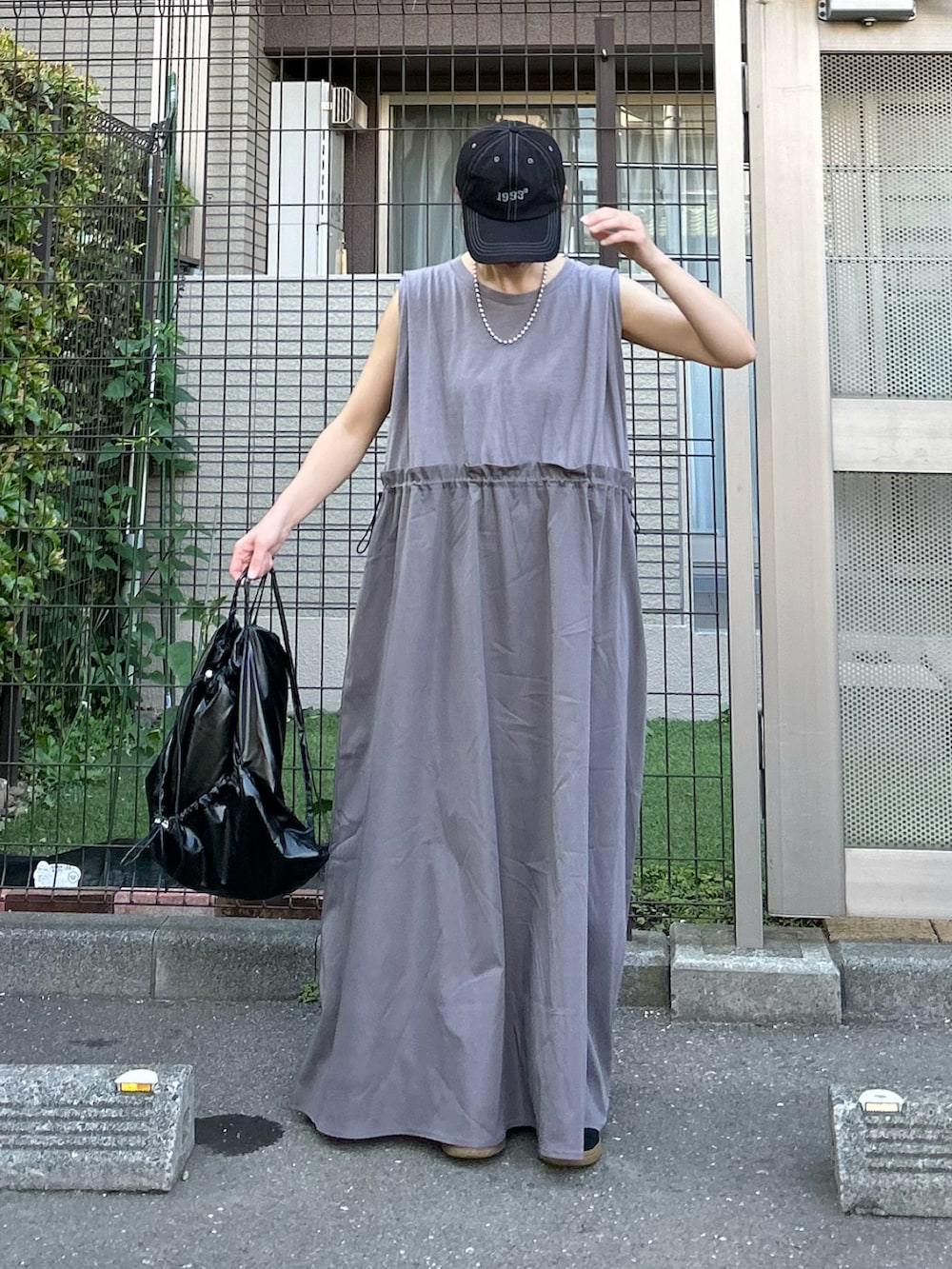 グレー系のワンピース、ブラック系のバックパック/リュック、ブラック系のキャップを着用したレディースの夏コーディネートの2枚目の写真