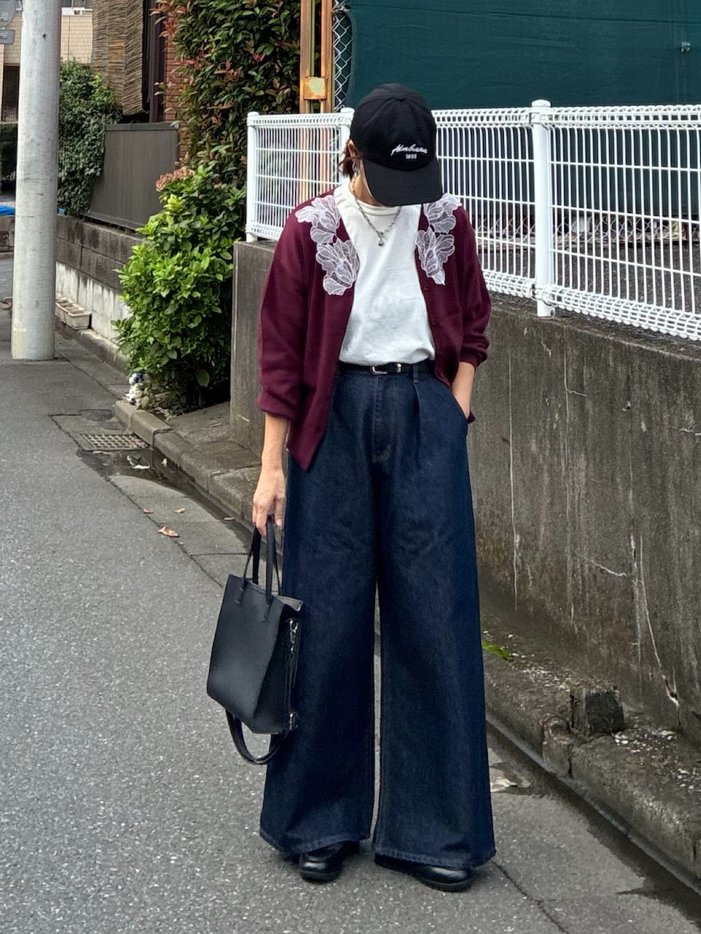 レッド系のカーディガン/ボレロ、ブラック系のTシャツ/カットソー、ブルー系のデニムパンツを着用したレディースの秋コーディネートの3枚目の写真