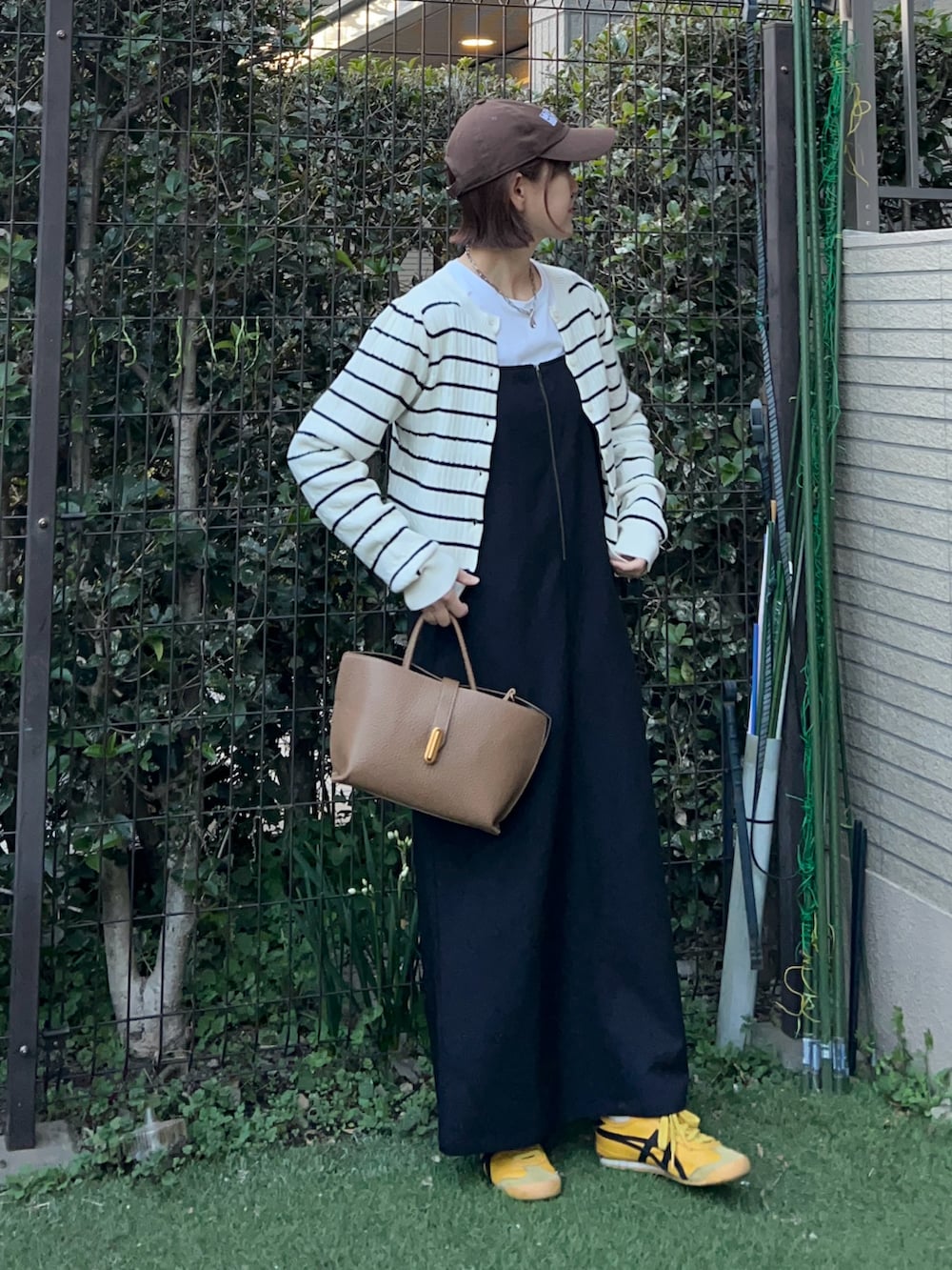 ブラウン系のハンドバッグ、ブラック系のワンピース、ホワイト系のカーディガン/ボレロを着用したレディースの冬コーディネートの3枚目の写真