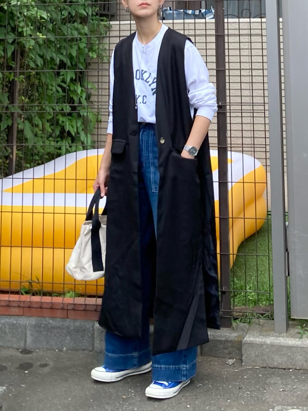 ホワイト系のTシャツ/カットソー、ブラック系のベスト、ブルー系のデニムパンツを着用したレディースの秋コーディネートの2枚目の写真