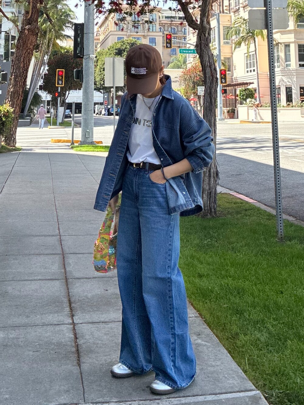 ブルー系のデニムジャケット、シルバー系のスニーカー、ホワイト系のTシャツ/カットソーを着用したレディースの春コーディネートの2枚目の写真