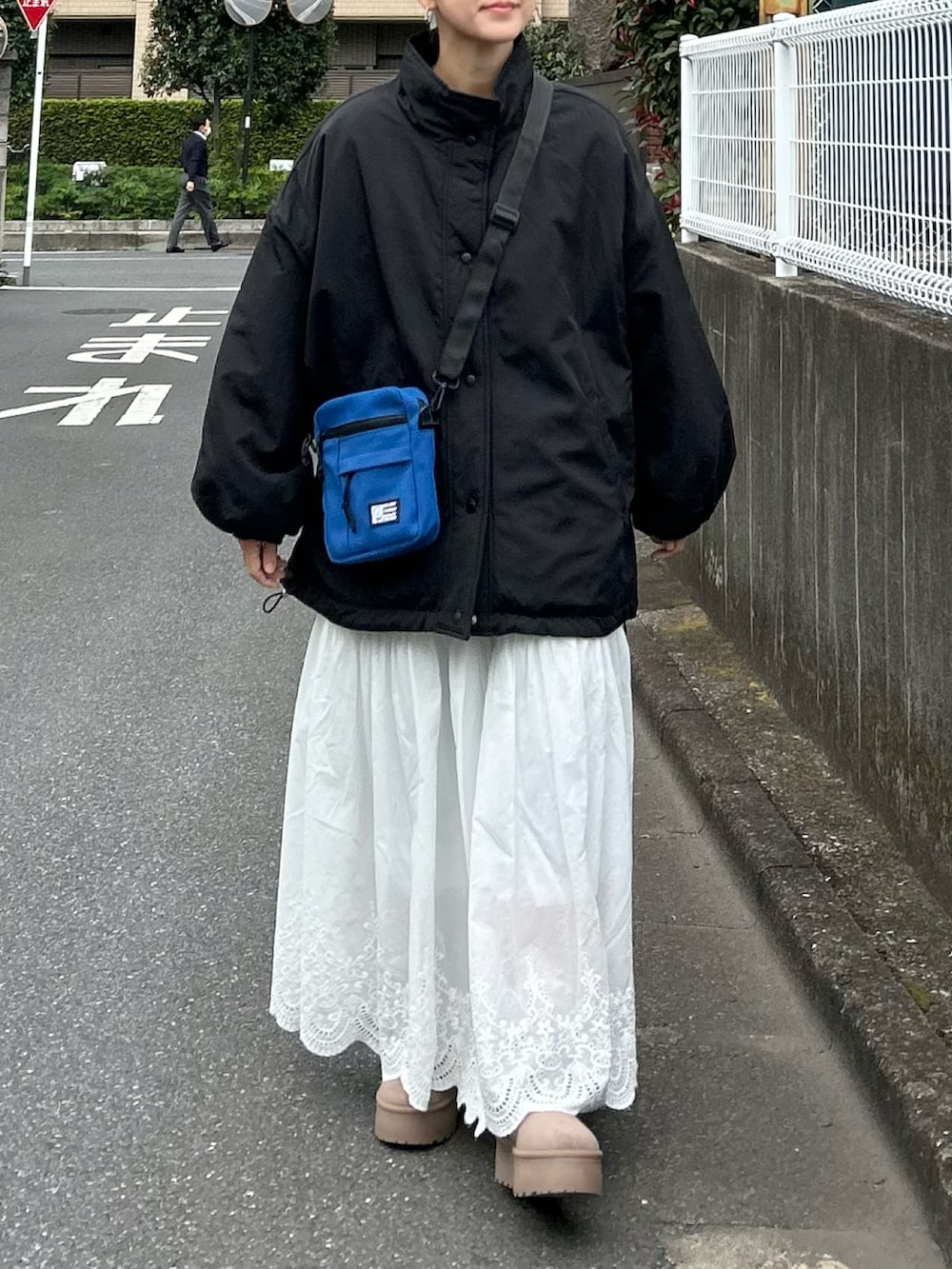 ブラック系のブルゾン、ベージュ系のブーツ、ホワイト系のスカートを着用したレディースの秋コーディネートの4枚目の写真