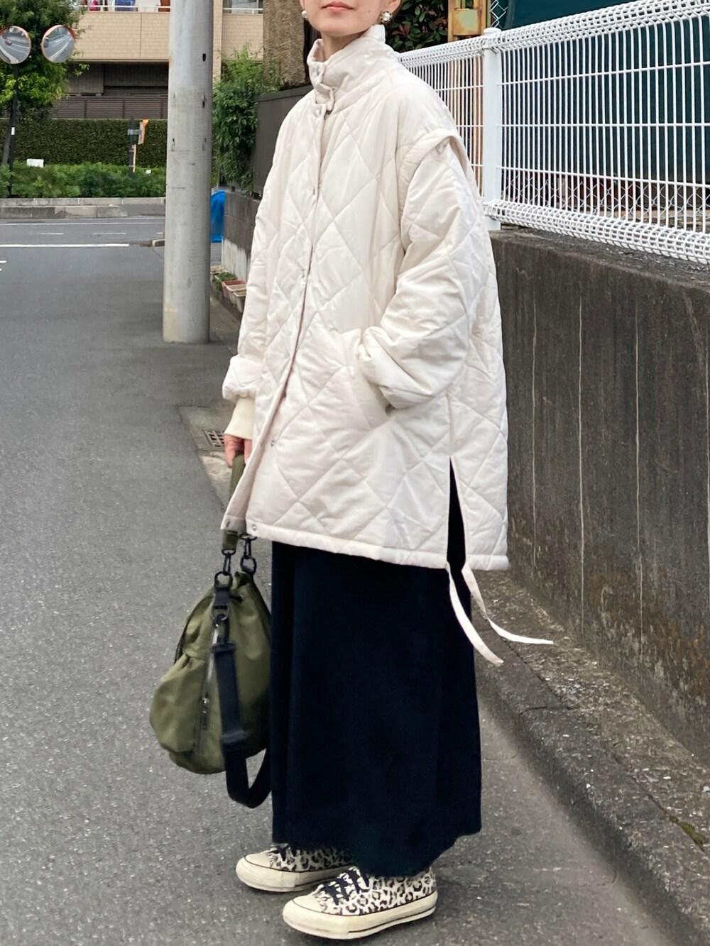 ホワイト系のブルゾン、ブラック系のワンピース、グリーン系のショルダーバッグを着用したレディースの秋コーディネートの2枚目の写真