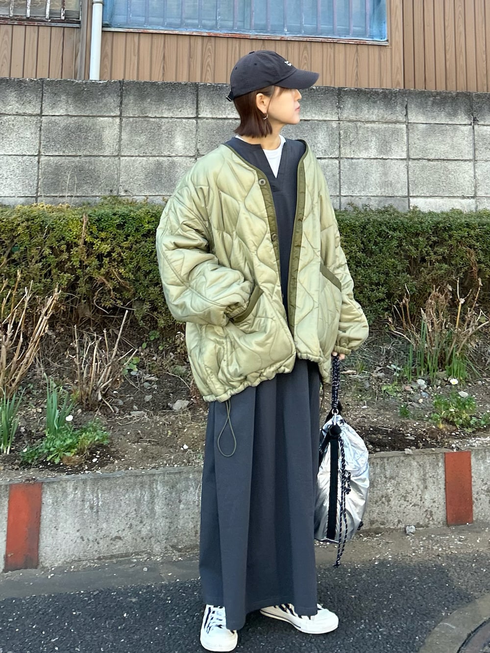 グリーン系のブルゾン、シルバー系のトートバッグ、グレー系のワンピースを着用したレディースの冬コーディネートの2枚目の写真