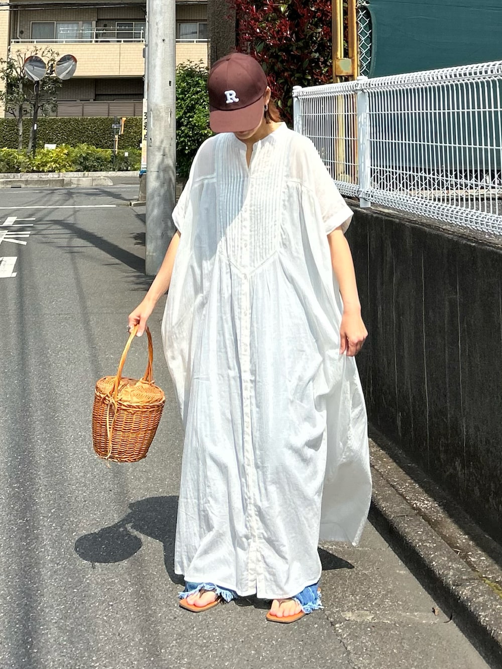 ホワイト系のワンピース、ブルー系のデニムパンツ、ブラウン系のキャップを着用したレディースの夏コーディネートの2枚目の写真