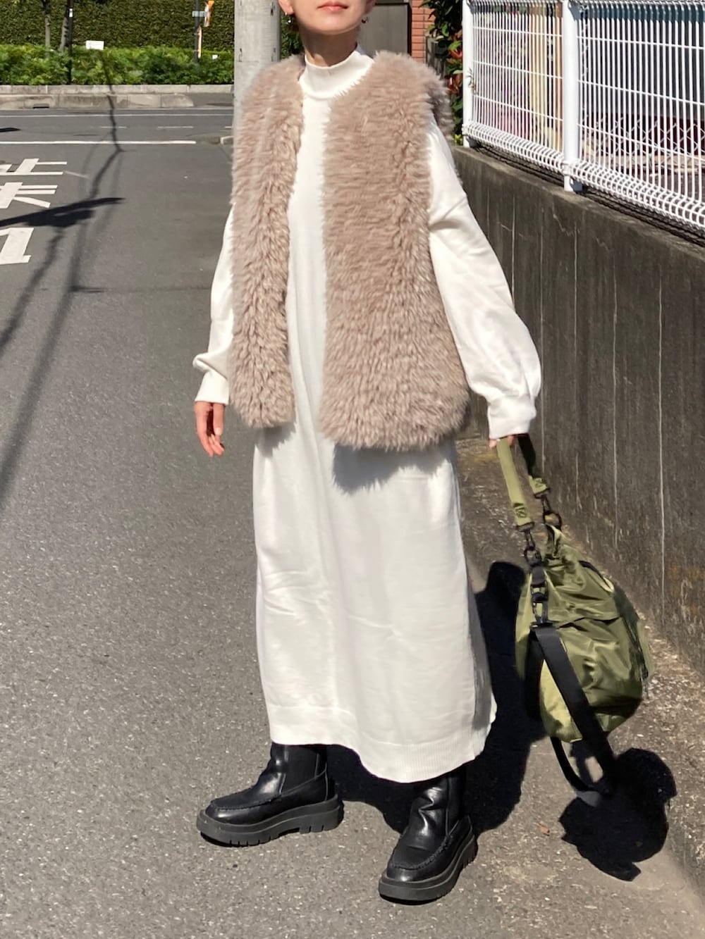 ホワイト系のワンピース、ベージュ系のベスト、グリーン系のショルダーバッグを着用したレディースの秋コーディネートの2枚目の写真