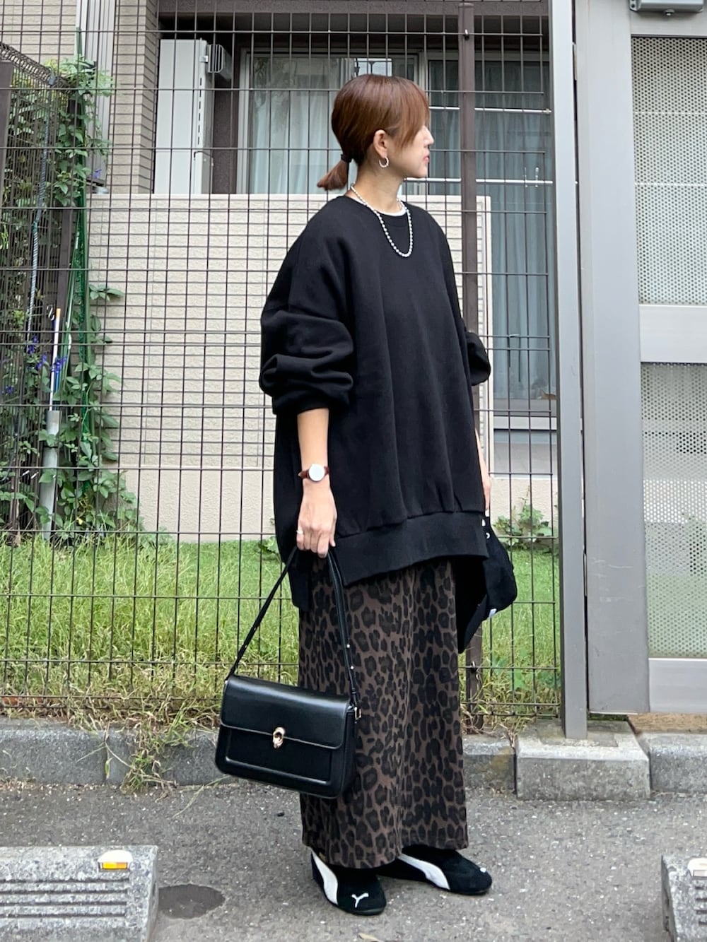 ブラック系のスウェット、ブラウン系のスカート、ブラック系のハンドバッグを着用したレディースの冬コーディネートの2枚目の写真