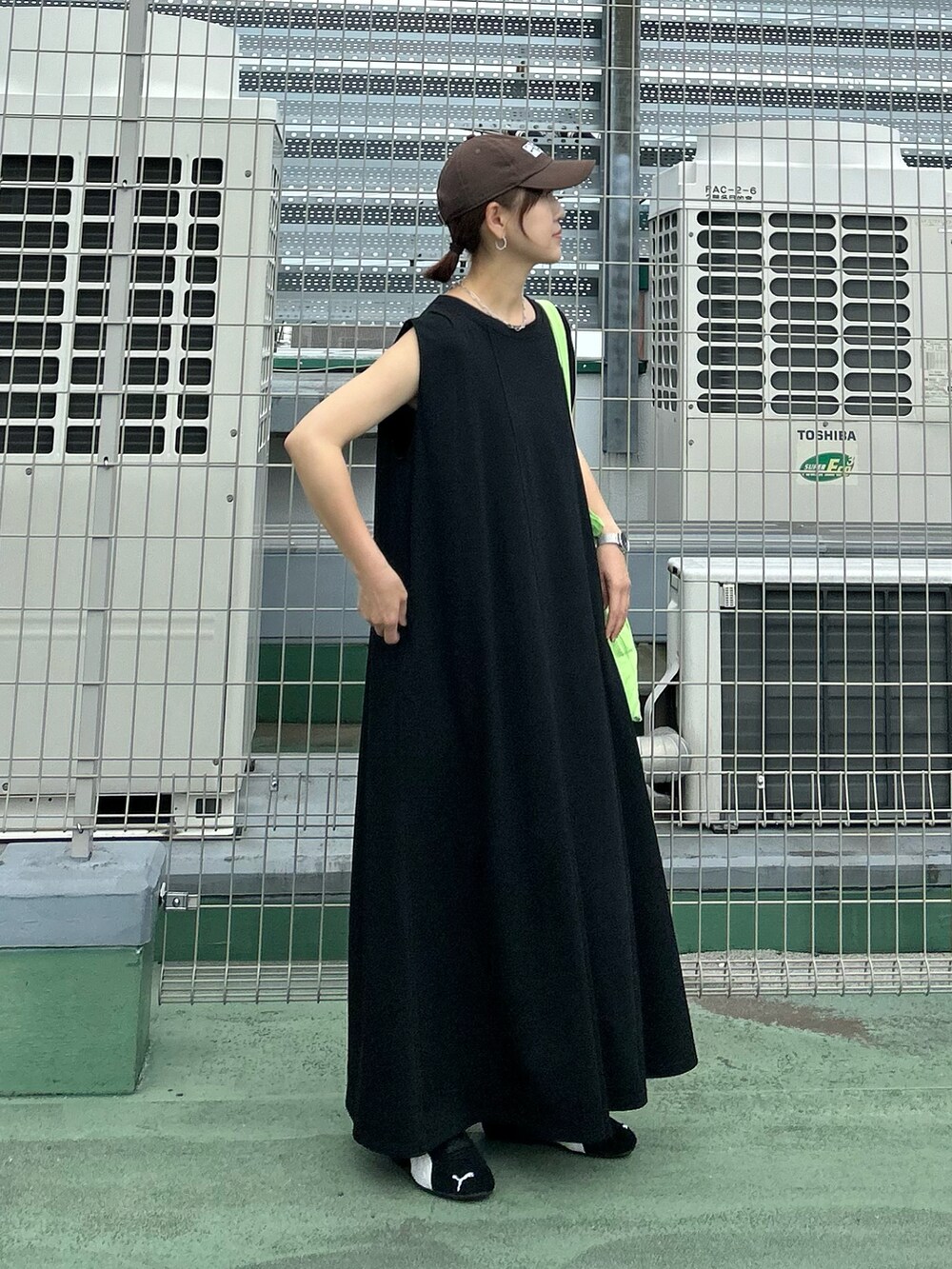 ブラック系のワンピース、グリーン系のトートバッグ、ブラック系のスニーカーを着用したレディースの夏コーディネートの2枚目の写真