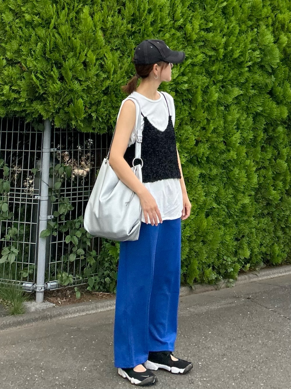 ブラック系のベスト、ブルー系のスカート、シルバー系のショルダーバッグを着用したレディースの夏コーディネートの2枚目の写真