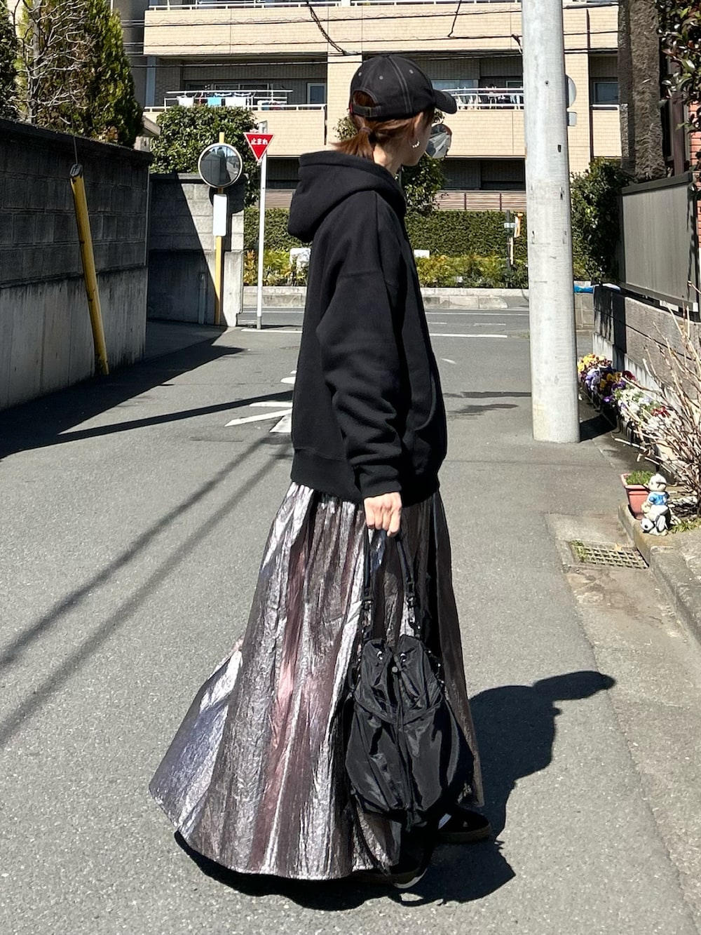 ブラック系のパーカー、シルバー系のスカート、ブラック系のショルダーバッグを着用したレディースの春コーディネートの2枚目の写真