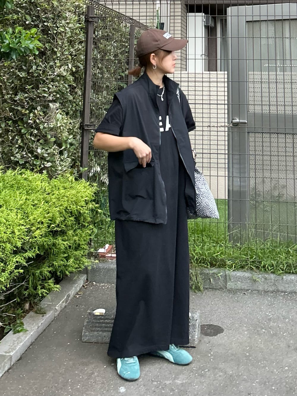 ブラック系のベスト、ブラック系のワンピース、グリーン系のスニーカーを着用したレディースの秋コーディネートの2枚目の写真