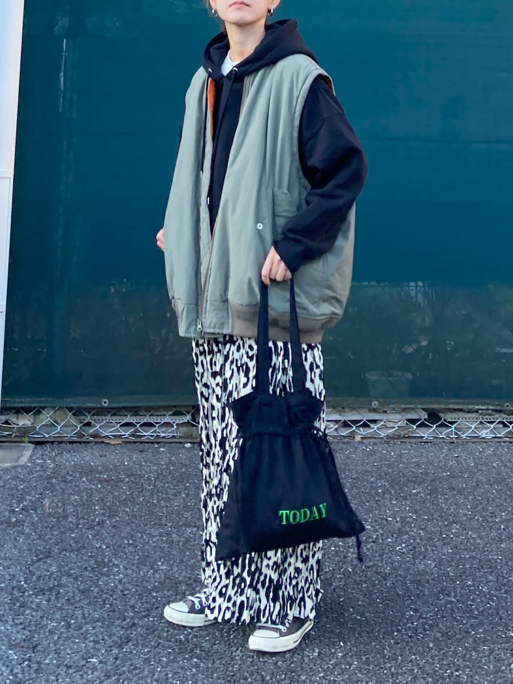 ブラック系のパーカー、ベージュ系のスカート、ブラック系のトートバッグを着用したレディースの秋コーディネートの3枚目の写真